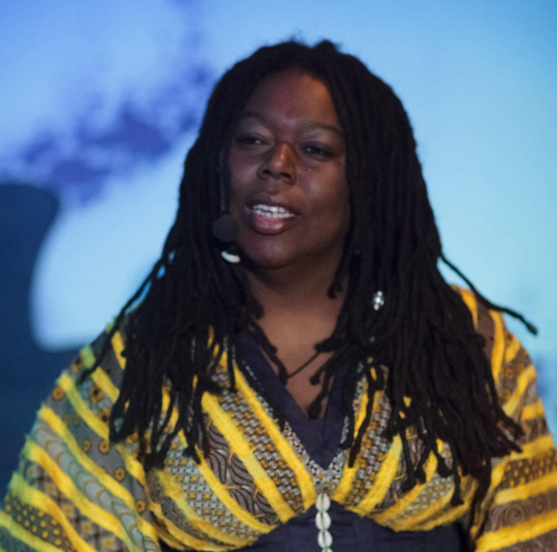 a black woman with long dark hair wearing a yellow and black dress