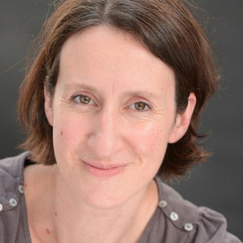 a white woman with short dark hair wearing a grey t-shirt