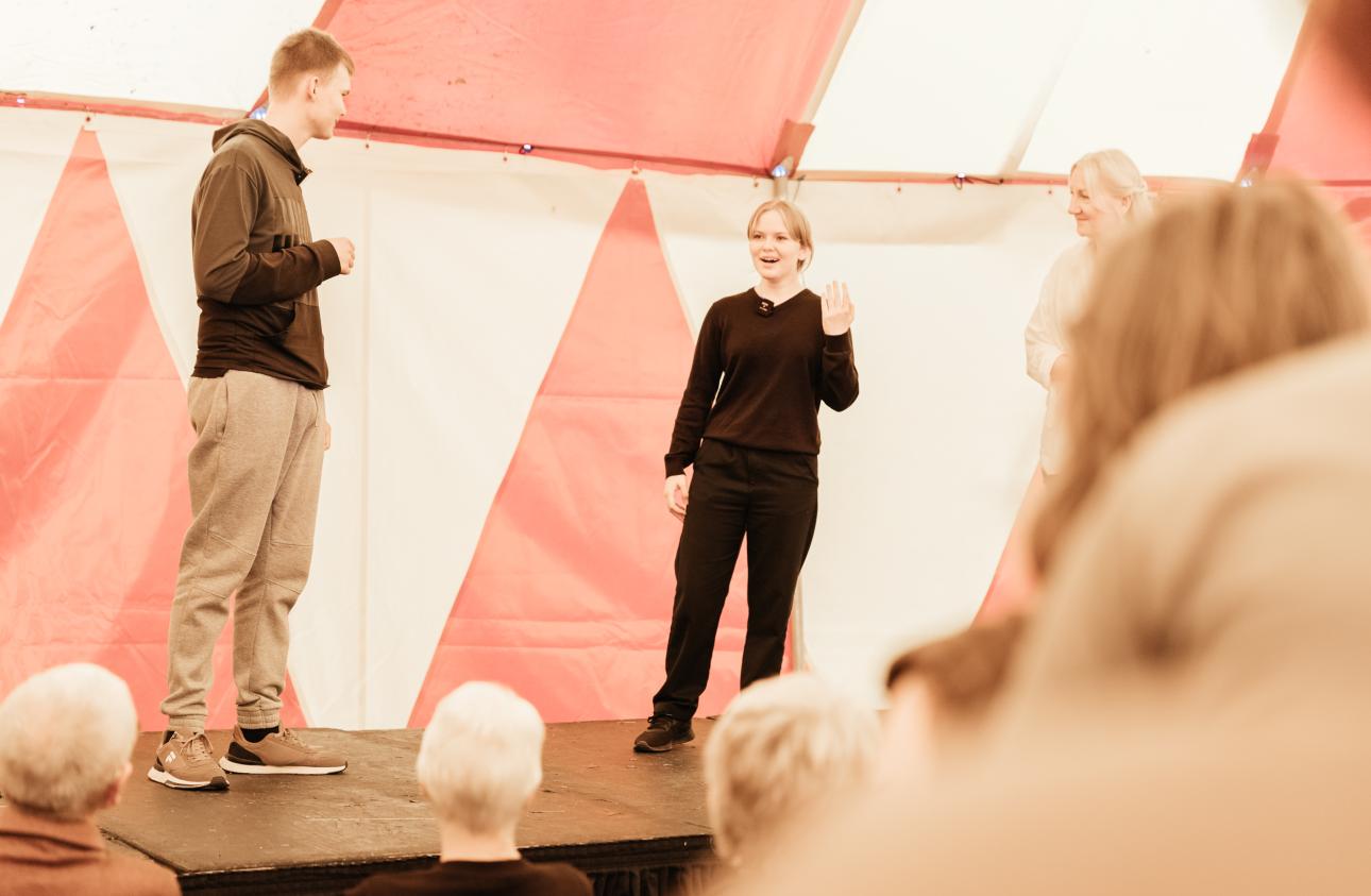 two young people perform on stage in the big top, storyteller maria whatton is also there at tapton lock festival