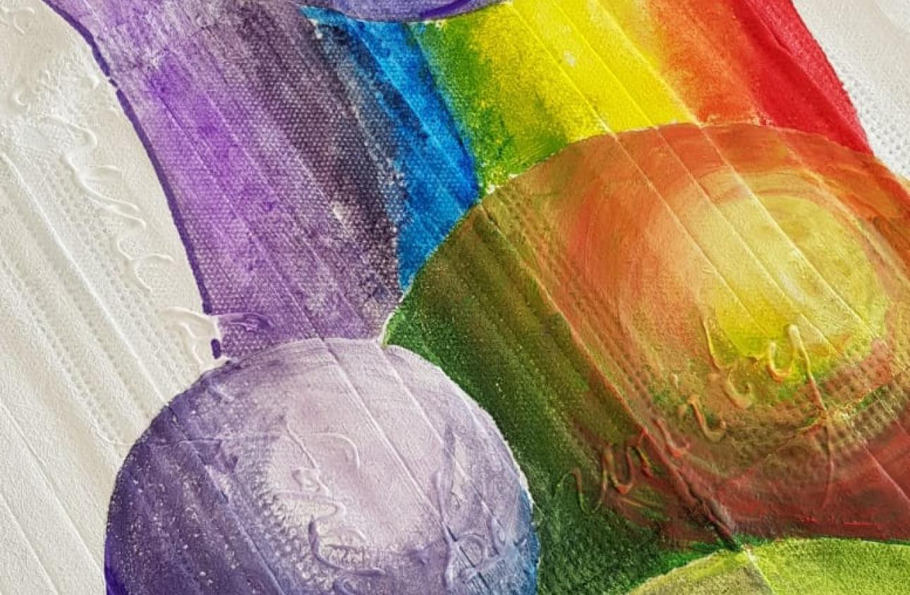 a close up of artwork featuring a brightly coloured rainbow, planets and words