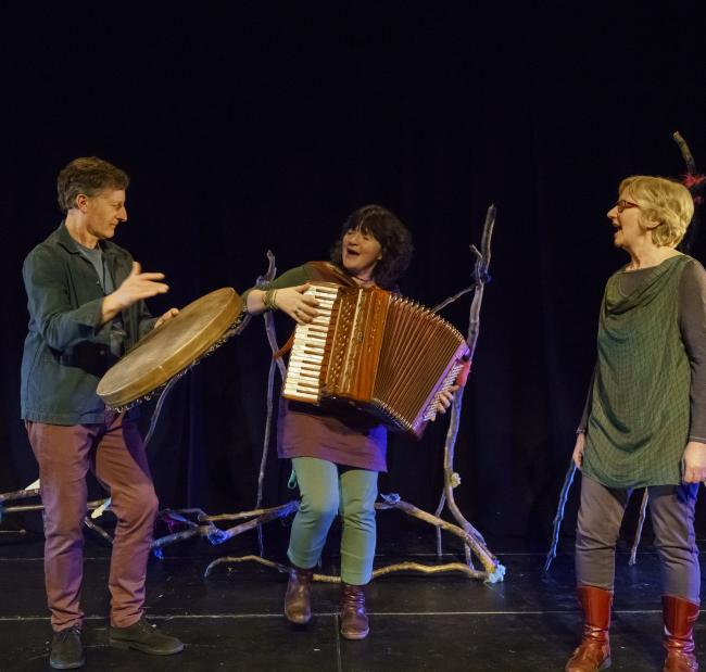 three artists on stage, (l-r) Michael Harvey plays the bodhran, Stacey Blythe plays the accordion and Lynne Denman sings
