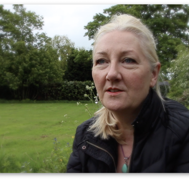 maria whatton a white woman with long blond hair sitting outside with green grass behind her