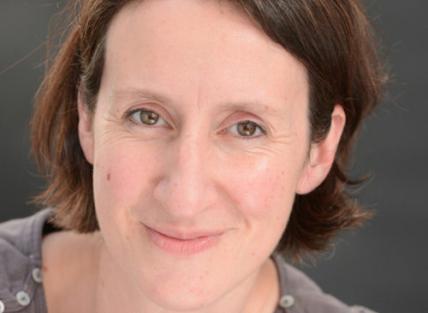 a white woman with short dark hair wearing a grey t-shirt