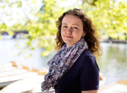 a white woman with long curly brown hair wearing a colourful scarf