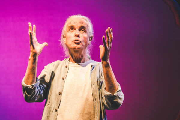 Hugh Lupton telling a story and looking and holding his hands up to the sky