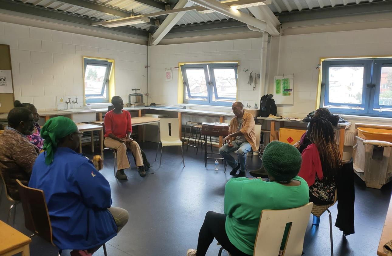 A group of people are sat in a circle sharing their stories inspired by the objects that they have found.