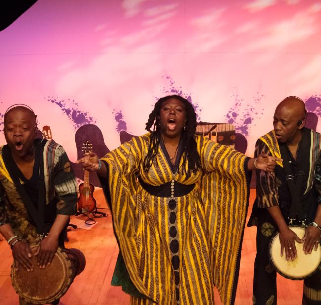 an ensemble shot of (L-R) Raymond Sereba, Jan Blake & Koumae Sereba performing on stage