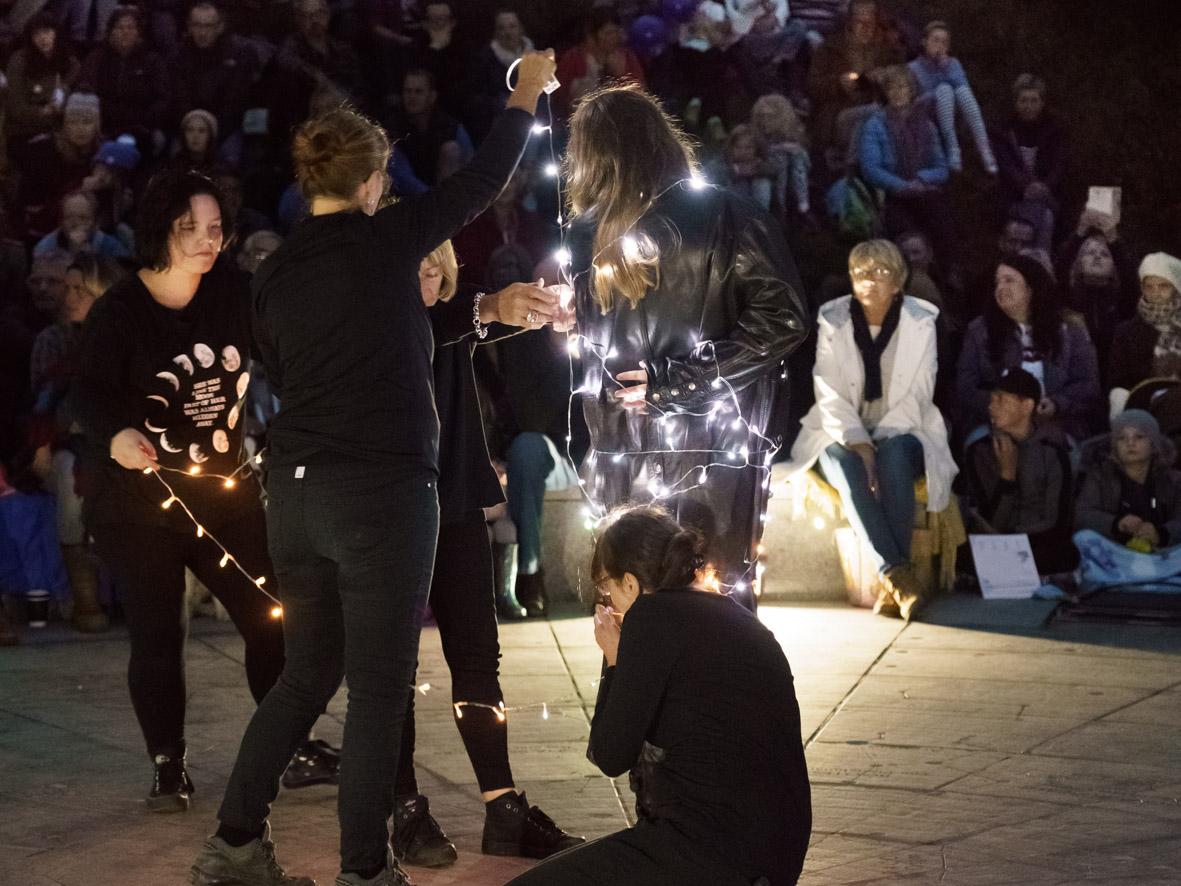 a group of performers at night at the stardisc in wirksworth winding fairy lights around each other