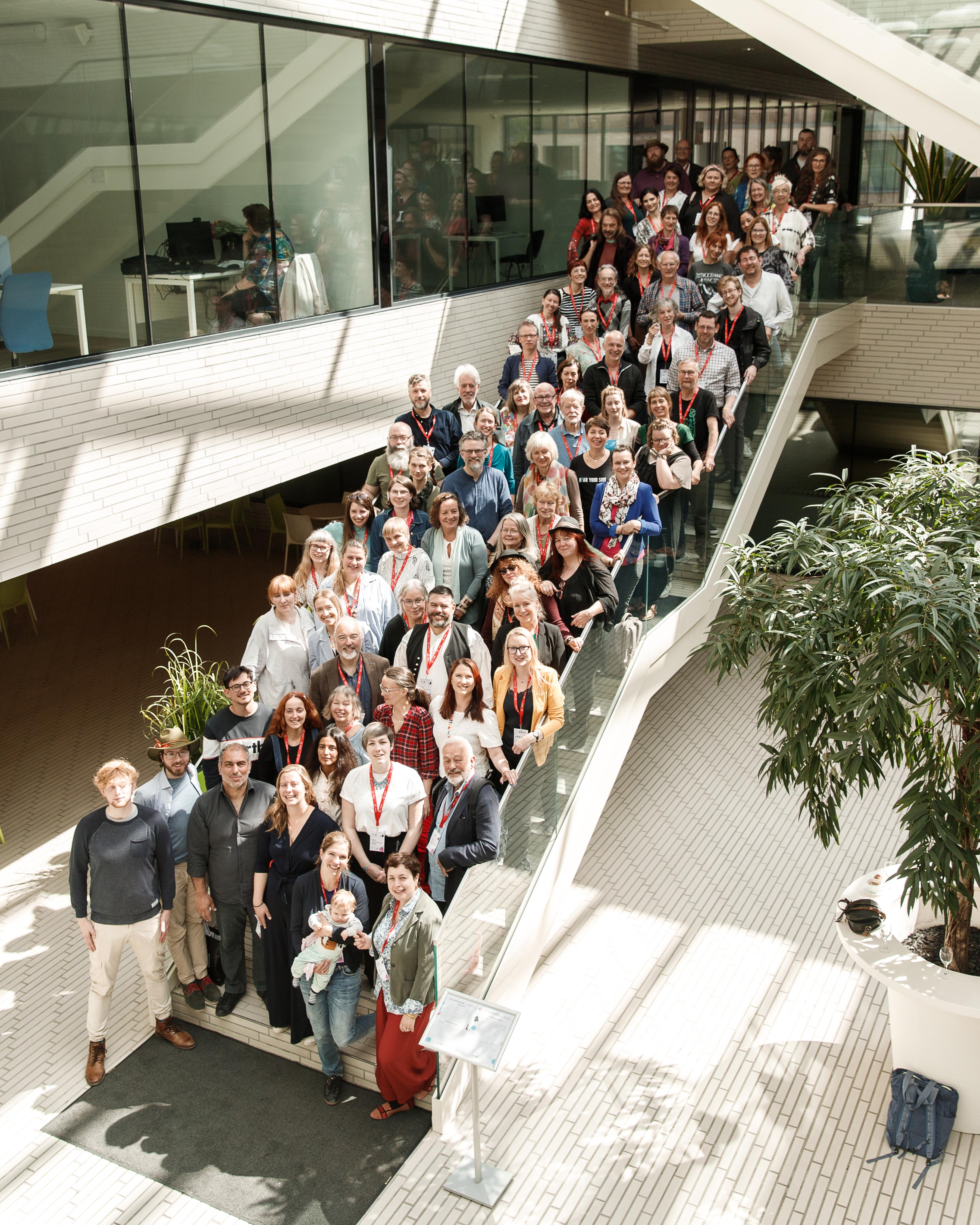 An image of the conference in 2022 with people standing on the stairs in a conference hall