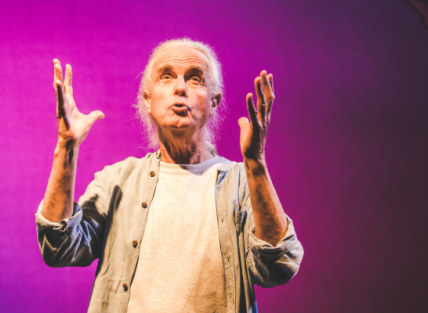 Hugh Lupton telling a story and looking and holding his hands up to the sky