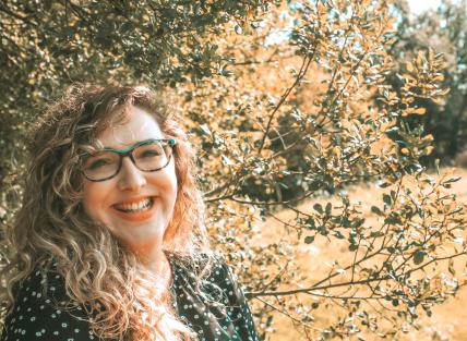 A photograph of Sarah who is wearing glasses and has long blonde brown wavy hair